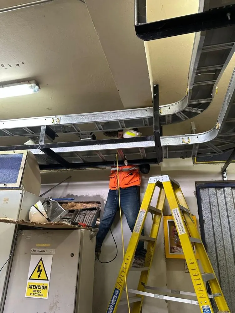 Técnico instalando bandejas portacables en sala eléctrica