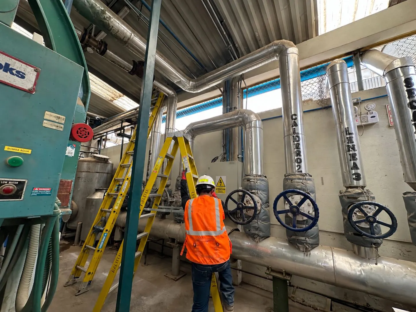 Técnico trabajando junto a tuberías y válvulas en planta